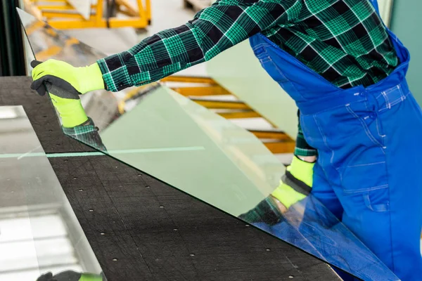 Camcı, cam bir bölmeyi özel bir masaya yerleştirir ve cam fabrikasında çalışır. 