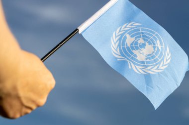 BM bayrağı bir kadının elinde gökyüzüne karşı Birleşmiş Milletler siyasi konsepti