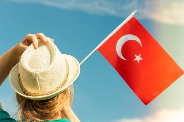 A young woman is holding a Turkish flag in her hand. Concept of a holiday travel destination and changing the official name of the country to Turkiye