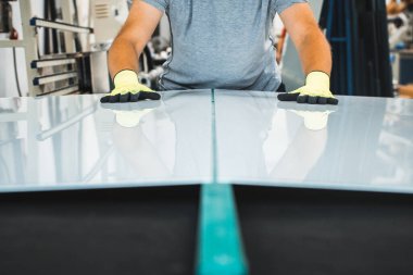 Camcı, profesyonel bir masadaki cam fabrikasında beyaz bir camı keser ve kırar.