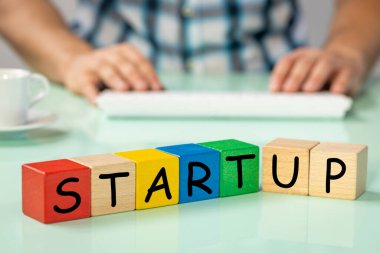 Renkli bloklara yazı yazmaya başlayın, arka planda bilgisayara, konsepte, iş dünyasına modern yaklaşıma, yenilikçi geliştirme yöntemlerine dayanan bir adam