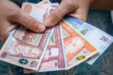 Guatemala 'nın parasını elinde tutan kadın, çeşitli quetzal banknotlar, iş ve finansal konsept