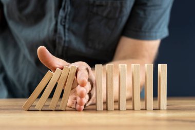 Businessman hand stop falling off wood block, planing and strategy concept, business disruption, company restructuring, action needed