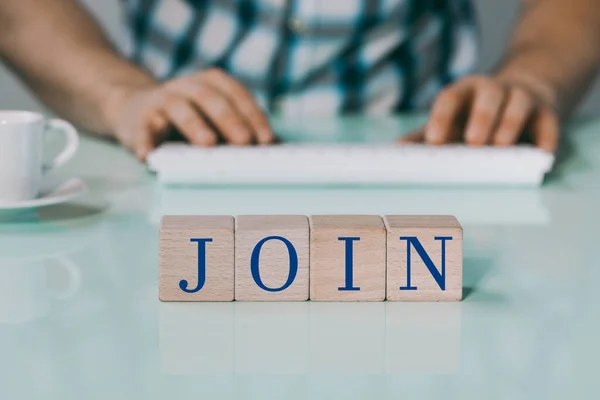 Creative Concept, recruiting for a job, Offer to join the team, The inscription Join on wooden blocks, Background, Man typing on the keyboard, a cup of coffee