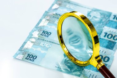 Brezilya parası, düz hesap, 100 reais banknot, büyüteç, beyaz zemin, iş ve finans konsepti, piyasa ve enflasyon gözlemi, para birimi istikrarı