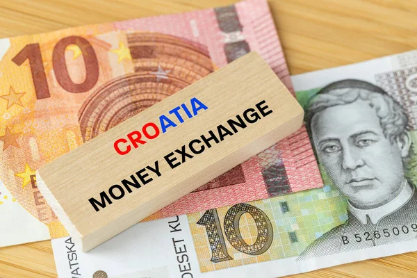Croatia\'s entry into the Euro zone, Wooden block with the words money exchange currencies, 10 Croatian kunas and 10 euros banknote