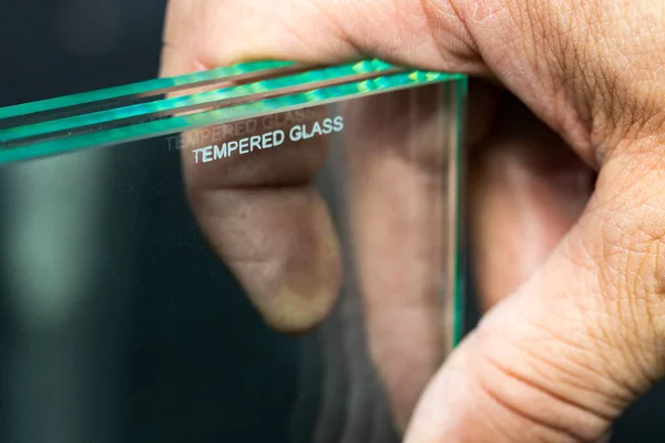 Toughened glass, protection of the glass pane in a special furnace, Inscription denoting ready and protected material against easy breakage. Glass industry, the glazier holds the finished glass in his hands