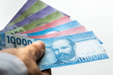 Chile money, paper pesos, held in hand on a white background, close up