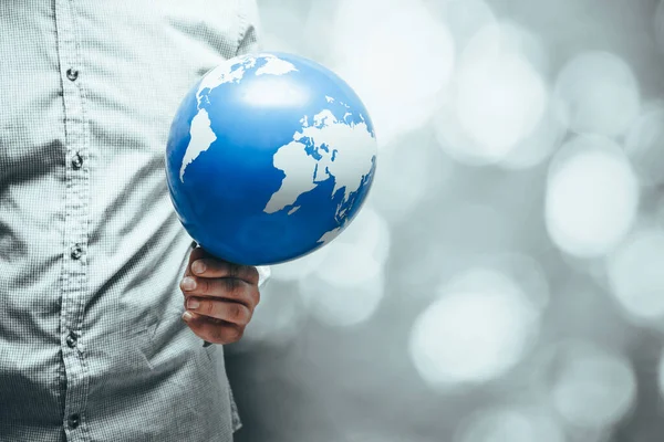 A man holds an earth shaped balloon in his red-hot hand, Artistic colors, Creative Ecological Concept, Global warming, Human influence on the planet, copy space