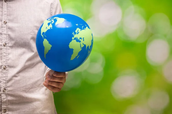 A man holds an earth shaped balloon in his red-hot hand, Artistic colors, Creative Ecological Concept, Global warming, Human influence on the planet, copy space