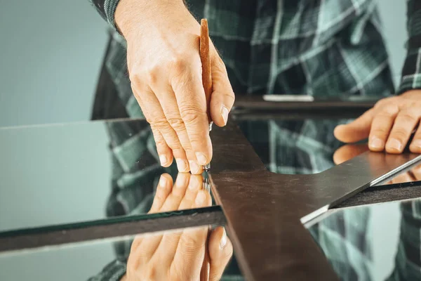 Glazier cuts the mirror, hand close-up with the cutter