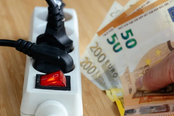 Increases in electricity prices in the European Union, Energy concept, Power strip with plugs connected and a large euro file in hand, Increase in energy prices for households and industry in Europe