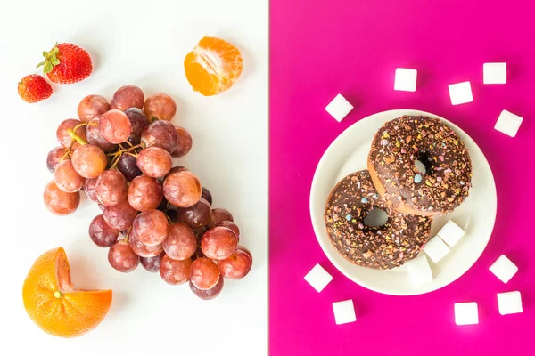 Healthy and unhealthy food, flat layer, two-color background, chocolate donuts with sprinkles on a fuchsia background, juicy and delicious fruit on white, natural sugar vs harmful processed