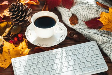 Beyaz bilgisayar klavyesi, renkli sonbahar yaprakları, kahve fincanı, sıcak kazak, konsept, yaşam tarzı, çalışma, rahatlama.