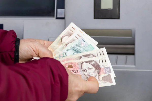 woman counts money withdrawn from an ATM, Czech koruna, financial concept