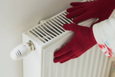 Ev ve ısıtma masrafları. Artan enerji fiyatları, yün eldivenli bir kadın soğuk bir radyatöre dokunuyor, kış ve soğuktan korkuyor, elektrik ve gaz kesintileri...