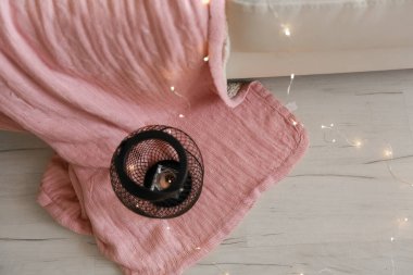 Metal bir şamdan yerde duruyor ve altında pembe bir battaniye.