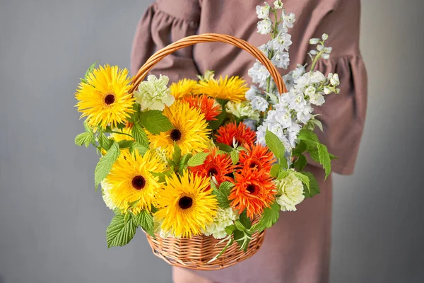 Flower arrangement in Wicker basket. Beautiful bouquet of mixed flowers in woman hand. Handsome fresh bouquet. Small flower shop and Flowers delivery.