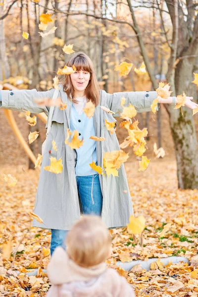 Porträts eines süßen 1-jährigen Mädchens und ihrer jungen Mutter. Wandern im Yellow Autumn Park. Laubfall und gelbe Blätter. sonniger Tag — Stockfoto