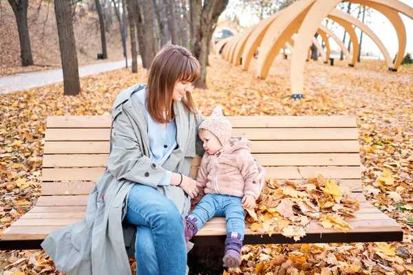 Portraits of a cute 1 year old baby girl and her young mother. Walking in Yellow Autumn Park. Leaf fall and yellow leaves. sunny day — Stock Photo, Image