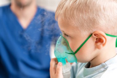 Bir çocuk doktoru akciğer hastalığını teşhis eder ve tedavi sağlar. İlacı nebulizör spreyiyle solu. Doktoru ziyaret eden sevimli küçük çocuğun portresi..