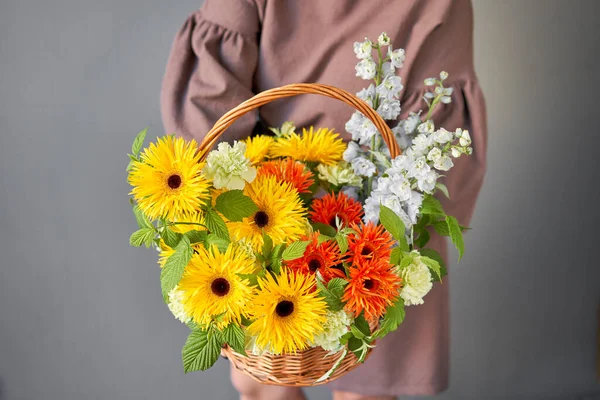 Flower arrangement in Wicker basket. Beautiful bouquet of mixed flowers in woman hand. Handsome fresh bouquet. Small flower shop and Flowers delivery. — Stock Photo, Image