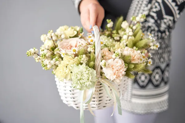Σύνθεση με λουλούδια σε ψάθινο καλάθι. Όμορφο μπουκέτο από μικτά λουλούδια στο χέρι της γυναίκας. Όμορφο φρέσκο μπουκέτο. Μικρό ανθοπωλείο και παράδοση λουλουδιών. — Φωτογραφία Αρχείου