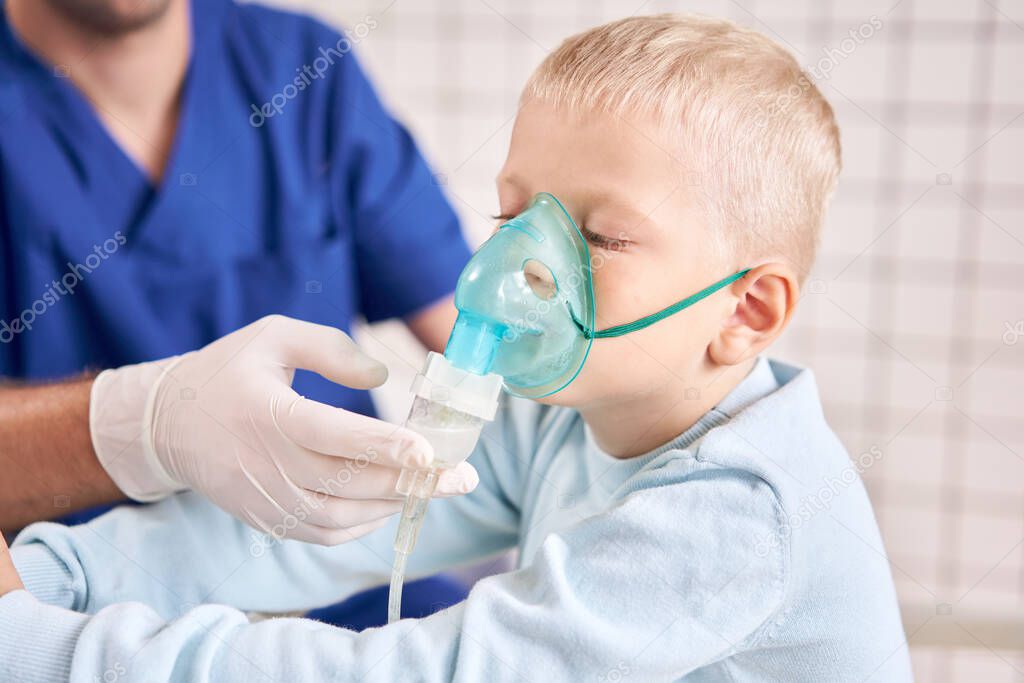 A pediatrician diagnoses lung disease and provides treatment. Breathe the medicine through a nebulizer inhaler.. Portrait of adorable little boy visiting doctor.