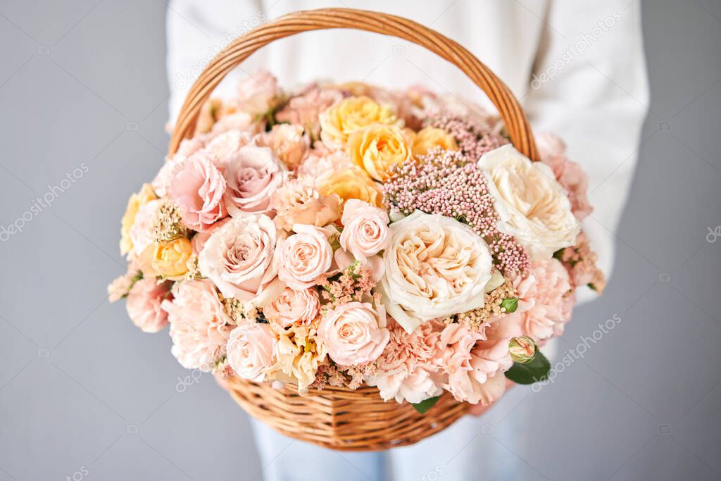 Flower arrangement in Wicker basket. Beautiful bouquet of mixed flowers in woman hand. Handsome fresh bouquet. Small flower shop and Flowers delivery.