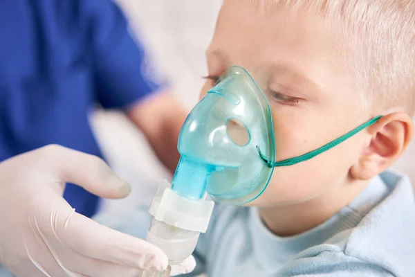 A gyermekorvos diagnosztizálja a tüdőbetegséget, és biztosítja a kezelést. Lélegezze be a gyógyszert porlasztó inhalátorral. Aranyos kisfiúról készült portré, aki orvoshoz megy.. — Stock Fotó