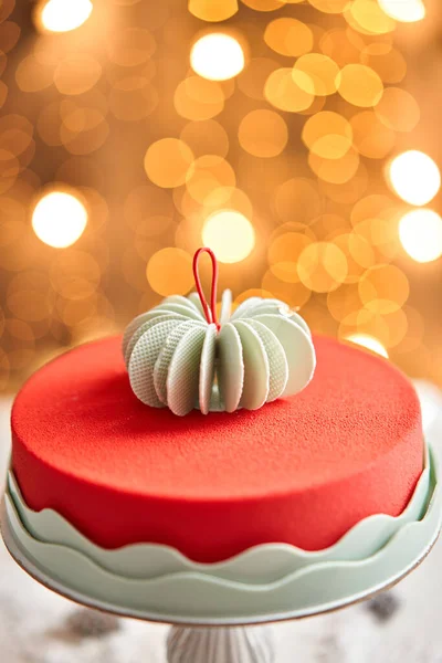Moussekuchen bedeckt mit rotem Velours. Girlandlampen bokeh auf dem Hintergrund. Moderner europäischer Kuchen. Französische Küche. Weihnachtsthema. Kopierraum — Stockfoto