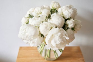 Cam vazoda beyaz şakayıklar. Katalog ya da internet mağazası için güzel şakayık çiçekleri. Çiçek dükkanı konsepti. Taze kesilmiş güzel bir buket. Çiçek teslimatı