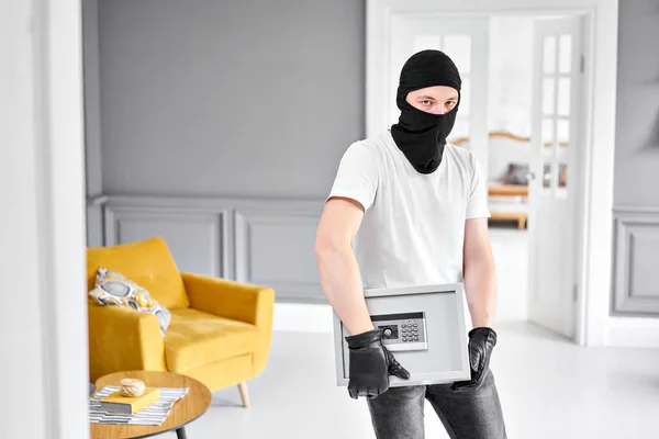 Tjuv med svart mask stjäla modern metall säker med ett elektroniskt lås. Begreppet hemstöld av pengar och dokument. — Stockfoto