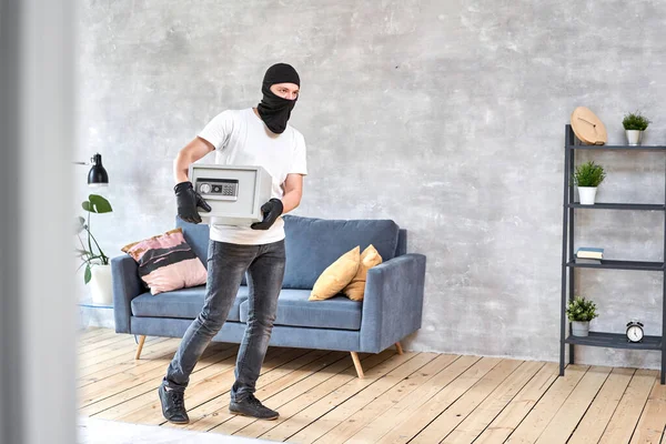 Tjuv med svart mask stjäla modern metall säker med ett elektroniskt lås. Begreppet hemstöld av pengar och dokument. — Stockfoto