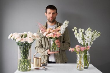 Erkek çiçekçi, adım adım vazoya çiçek yerleştiriyor. Çiçek demeti, eve gitmek için hazır. Dekorasyon için taze kesilmiş çiçekler. Avrupa çiçekçisi. Taze kesilmiş çiçek getirdim..