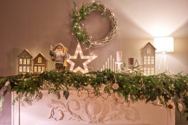 Madalyalı şömine. Noel ağacı. Küçük bir ev, koniler, çelenkler ve diğer Noel ağacı oyuncakları. Çelenklerden gelen ışık