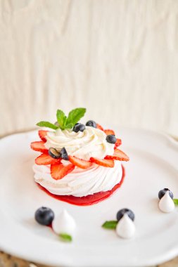 Pavlova kıtır kıtır kabuklu kremalı bir tatlıdır. Süslü çilek, nane yaprağı, yabanmersini ve krema. Lokanta, tatlı yemek.