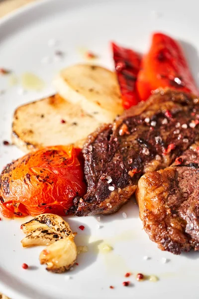 Hot Rib Eye Steak auf weißem Teller. Gegrilltes Gemüse garnieren. Speisekarte vom Grill. — Stockfoto