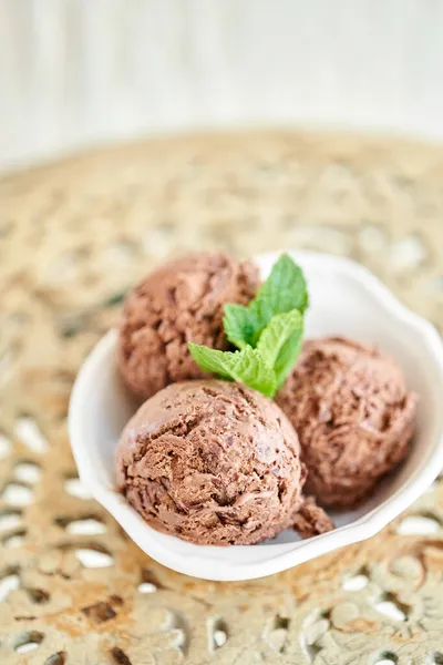 Шоколадное мороженое с мятной листочкой. три шара в белой чаше на винтажном столе. — стоковое фото
