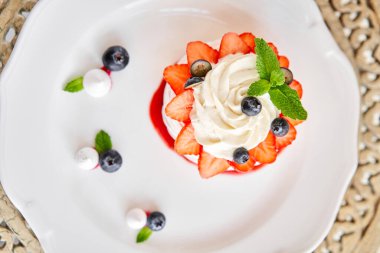 Pavlova kıtır kıtır kabuklu kremalı bir tatlıdır. Süslü çilek, nane yaprağı, yabanmersini ve krema. Lokanta, tatlı yemek.