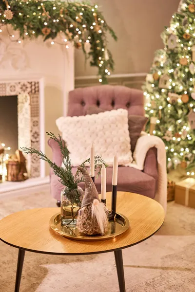 Díszített asztal a karácsonyi belső térben. Karácsonyfa. Közelkép egy kis ház, kúp, koszorú, és más karácsonyfa játékok. fény a koszorúból — Stock Fotó