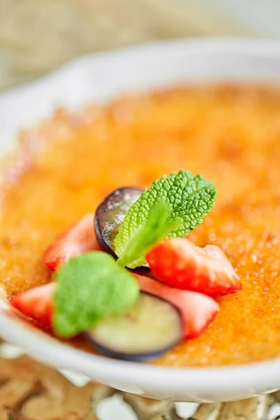 Classica creme brulee in ciotola di vetro. Gelato appetitoso da vicino. Delizioso dessert con uva e fragola Farina zuccherina con caramello, menta e frutti di bosco. Ristorante dolce cibo — Foto Stock