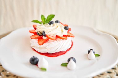 Pavlova kıtır kıtır kabuklu kremalı bir tatlıdır. Süslü çilek, nane yaprağı, yabanmersini ve krema. Lokanta, tatlı yemek.