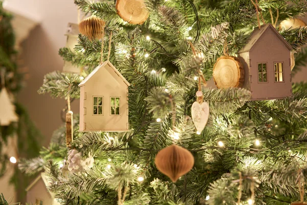 Arbre de Noël décoré. Gros plan d'une petite maison, de cônes, de guirlandes et d'autres jouets d'arbres de Noël. lumière des guirlandes — Photo