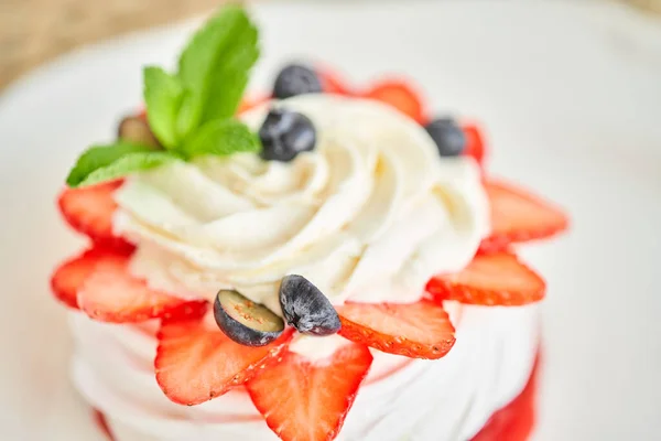 Pavlova is a meringue-based dessert with a crisp crust topped. Decorated strawberry, mint leaf, blueberry and whipped cream. Restaurant sweet food — Stock Photo, Image