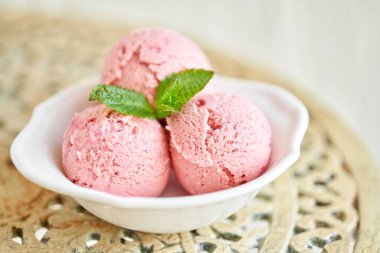 Nane yapraklı çilekli dondurma. Eski bir masada beyaz bir kasede üç top. şerbet