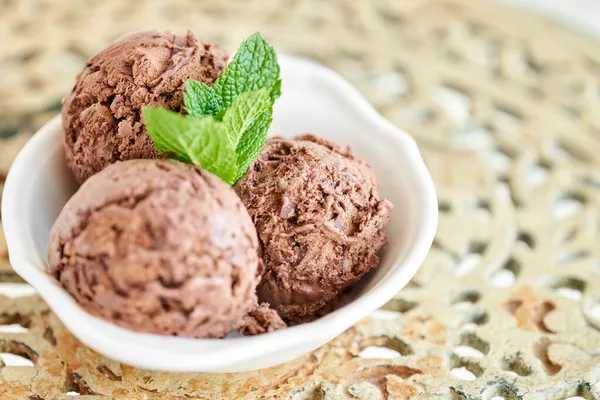 Nane yapraklı çikolatalı dondurma. Eski bir masada beyaz bir kasede üç top.. — Stok fotoğraf
