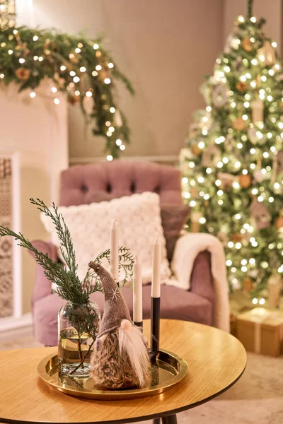 Mesa decorada en el interior de Navidad. Árbol de Navidad. Acercamiento de una pequeña casa, Conos, guirnalda, y otros juguetes del árbol de Navidad. luz de las guirnaldas — Foto de Stock