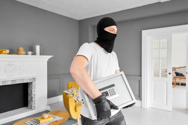 带着黑色面具的小偷用电子锁偷走了现代金属保险箱。1.偷窃钱财和文件概念. — 图库照片
