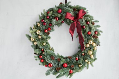 Gri duvarda taze ladin çelengi. Kırmızı, altın süslemeli ve taşaklı Xmas halkası. Noel havası.